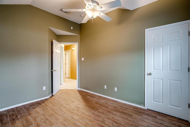 empty room with light hardwood / wood-style flooring, ceiling fan, and vaulted ceiling