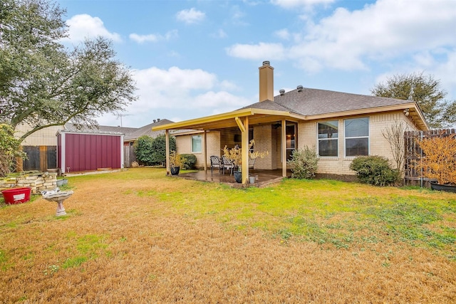 back of house featuring a lawn, a shed, and a patio area