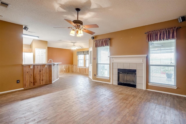 unfurnished living room with vaulted ceiling, light wood-type flooring, a textured ceiling, and a fireplace