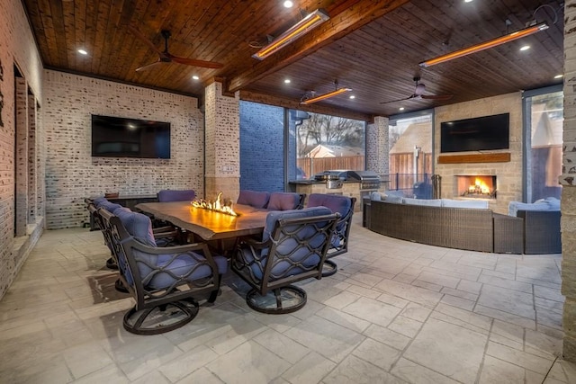 view of patio / terrace with ceiling fan, area for grilling, and an outdoor living space with a fireplace