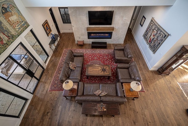 living room with a high ceiling, wood-type flooring, and a tile fireplace