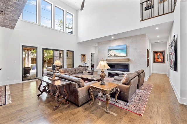 4737 Sugar Mill Rd, Dallas, TX 75244 - living room featuring wood-type flooring, a glass covered fireplace, a high ceiling, and baseboards
