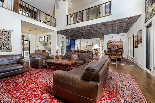 living room featuring a chandelier, dark hardwood / wood-style flooring, and a towering ceiling