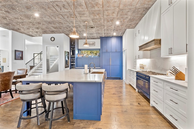 4737 Sugar Mill Rd, Dallas, TX 75244 - kitchen featuring a sink, an ornate ceiling, light wood-type flooring, double oven range, and an island with sink
