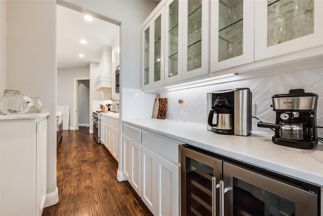 bar featuring dark hardwood / wood-style floors, tasteful backsplash, white cabinetry, wine cooler, and stainless steel appliances