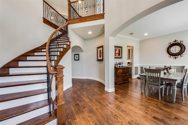 dining room with ornamental molding, a towering ceiling, and dark hardwood / wood-style floors