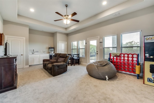 carpeted living room with a raised ceiling, a towering ceiling, and ceiling fan