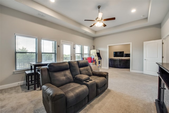 carpeted living room featuring ceiling fan and a tray ceiling