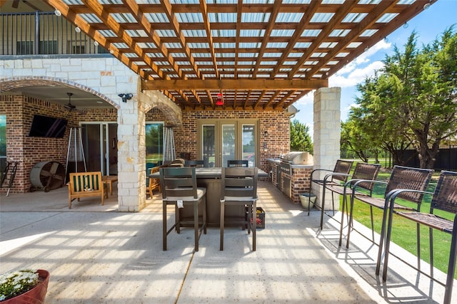 view of patio featuring exterior kitchen, area for grilling, ceiling fan, and a pergola