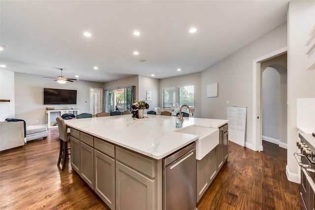 kitchen featuring a kitchen bar, sink, an island with sink, ceiling fan, and stainless steel appliances