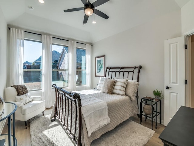 bedroom with ceiling fan, light hardwood / wood-style floors, and vaulted ceiling