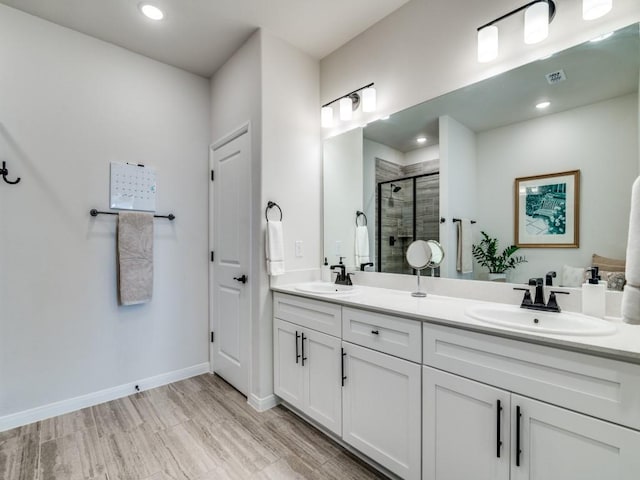 bathroom with a sink, baseboards, a shower stall, and wood finished floors