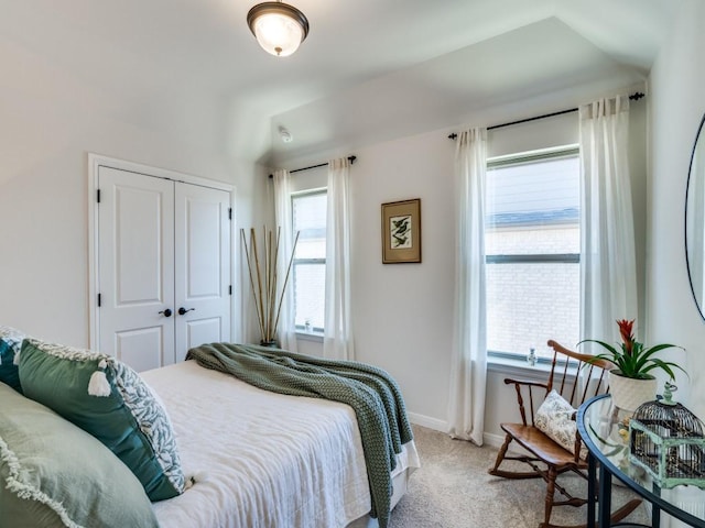 bedroom with a closet, light colored carpet, and baseboards