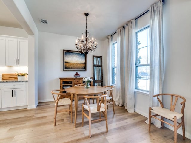 dining space with light wood finished floors, a notable chandelier, visible vents, and plenty of natural light