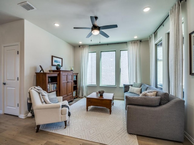 living area featuring plenty of natural light, visible vents, ceiling fan, and wood finished floors