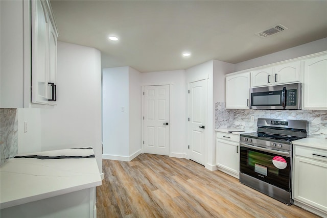 kitchen featuring white cabinetry, backsplash, light hardwood / wood-style flooring, and appliances with stainless steel finishes