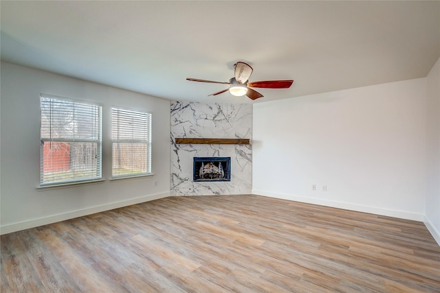 unfurnished living room with ceiling fan, a premium fireplace, and light hardwood / wood-style floors