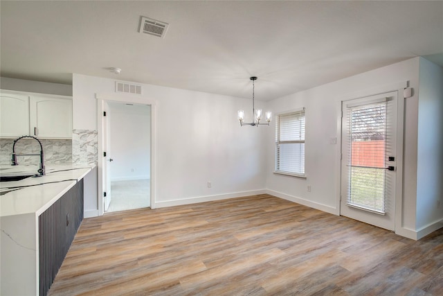 kitchen with white cabinetry, sink, light hardwood / wood-style floors, and hanging light fixtures