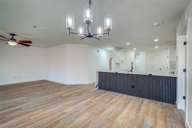 interior space featuring ceiling fan with notable chandelier and light hardwood / wood-style flooring