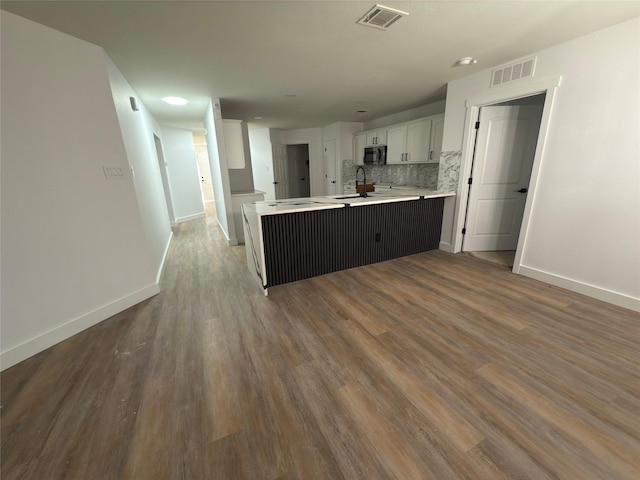 kitchen with white cabinetry, decorative backsplash, sink, kitchen peninsula, and hardwood / wood-style flooring