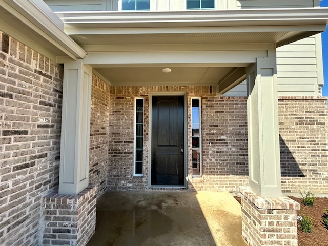 entrance to property featuring brick siding