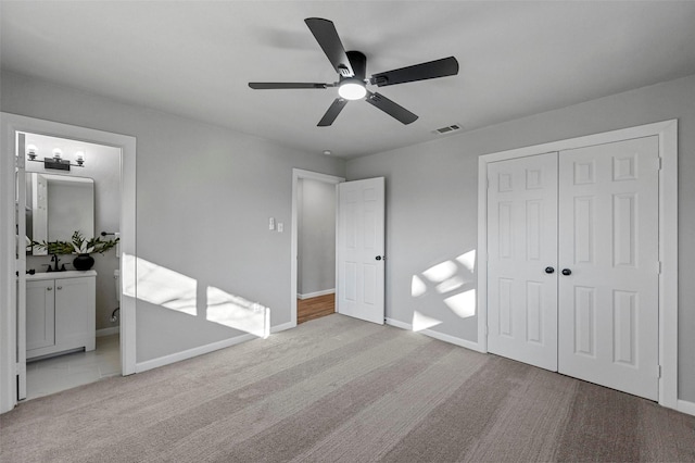 unfurnished bedroom with light carpet, ceiling fan, ensuite bathroom, sink, and a closet