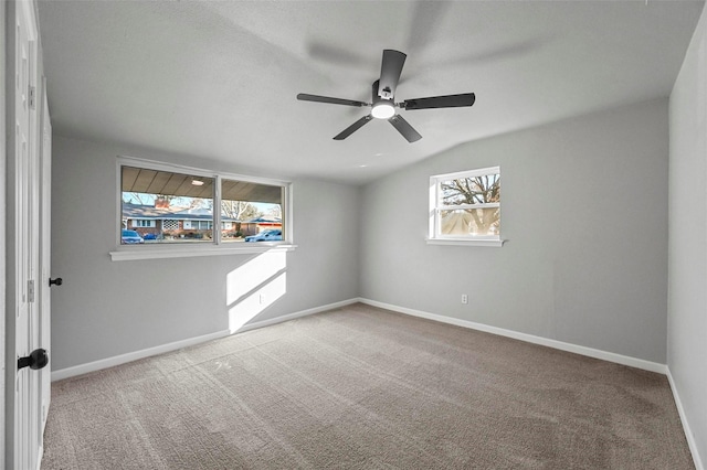 carpeted spare room with ceiling fan, plenty of natural light, and lofted ceiling