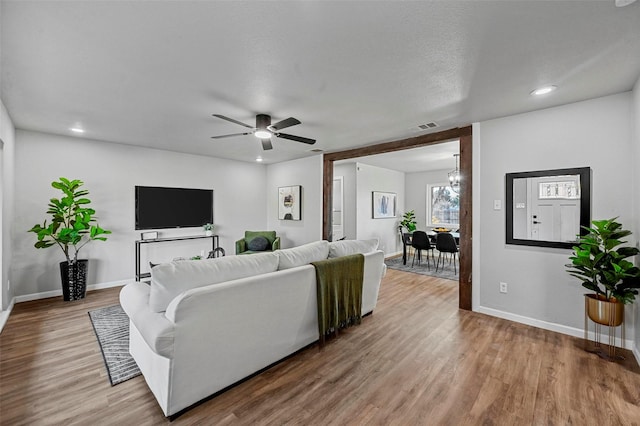 living room featuring hardwood / wood-style flooring, ceiling fan, and a textured ceiling