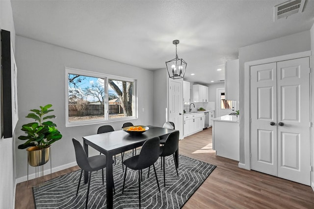 dining space with sink, hardwood / wood-style floors, and a notable chandelier