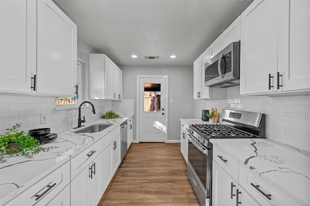 kitchen featuring light stone counters, sink, white cabinetry, and appliances with stainless steel finishes