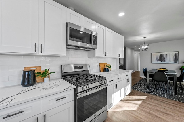 kitchen with light stone counters, white cabinets, dark hardwood / wood-style flooring, and stainless steel appliances