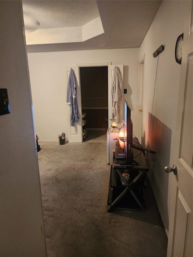 hall featuring a tray ceiling, a textured ceiling, and carpet flooring