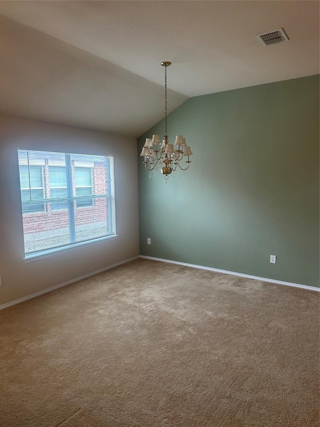 spare room featuring an inviting chandelier, carpet flooring, and vaulted ceiling