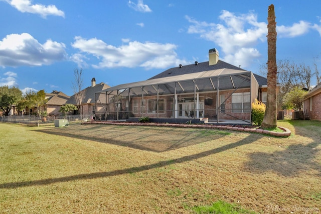 back of house with a lanai and a lawn