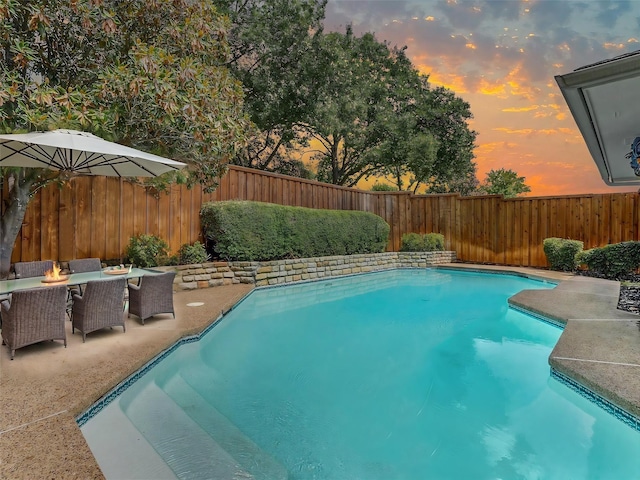 pool at dusk featuring a patio