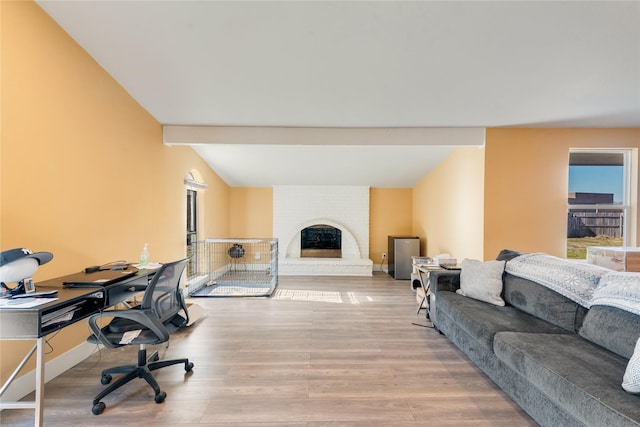 office with a brick fireplace, beam ceiling, and light hardwood / wood-style floors