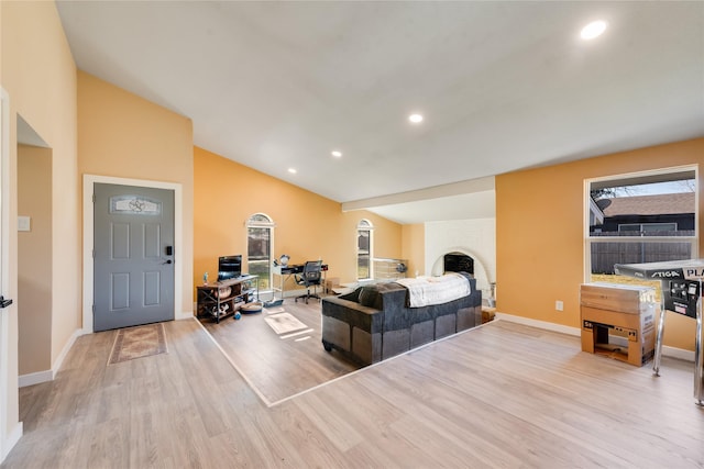 living room featuring a large fireplace, light hardwood / wood-style flooring, and lofted ceiling