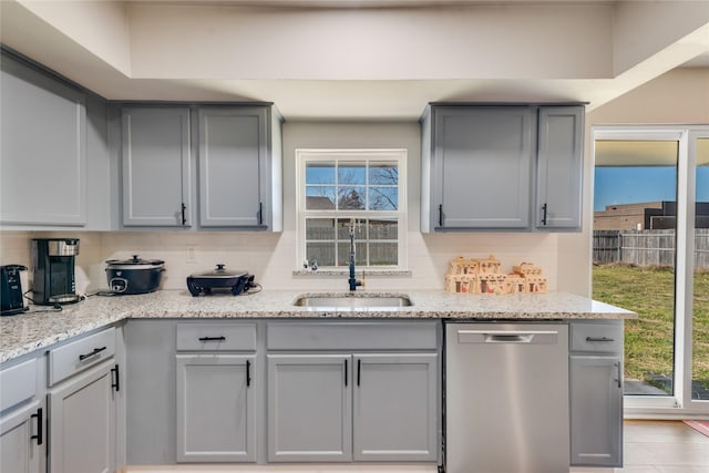 kitchen with dishwasher, decorative backsplash, sink, light stone counters, and gray cabinetry