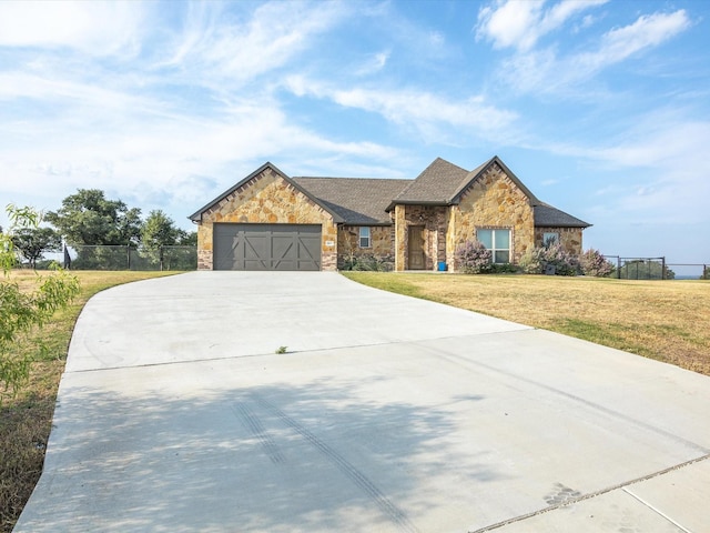 view of front of house featuring stone siding, an attached garage, a front yard, and fence