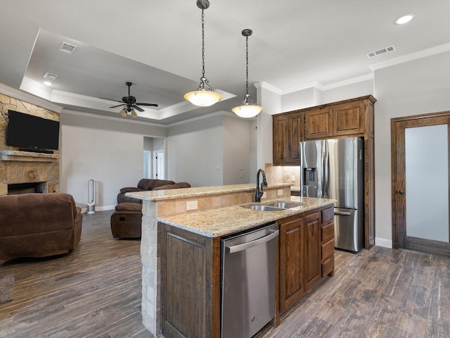 kitchen with dark wood-type flooring, stainless steel appliances, an island with sink, and sink