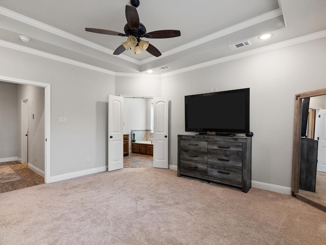 carpeted bedroom with ceiling fan, ensuite bathroom, ornamental molding, and a raised ceiling