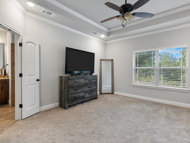 bedroom featuring light carpet, ceiling fan, ornamental molding, and a tray ceiling