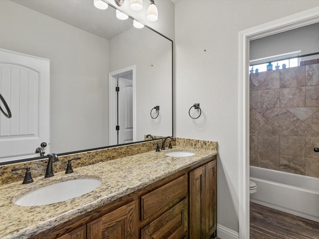 full bathroom with hardwood / wood-style floors, toilet, vanity, and tiled shower / bath