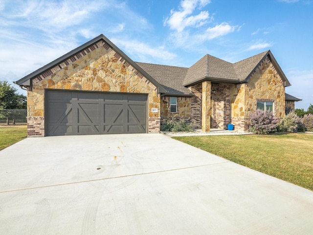 view of front of house featuring an attached garage, roof with shingles, concrete driveway, and a front yard