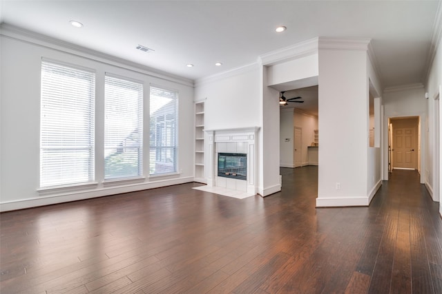 unfurnished living room with ceiling fan, crown molding, a fireplace, and built in shelves