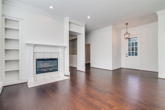 unfurnished living room featuring a chandelier, a tiled fireplace, ornamental molding, and hardwood / wood-style floors