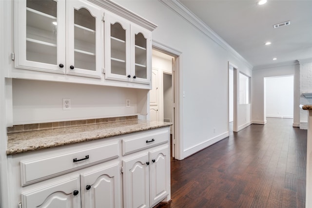 kitchen featuring dark wood-type flooring, white cabinetry, ornamental molding, and light stone countertops