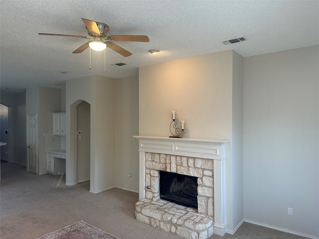 living room featuring a fireplace, light colored carpet, a textured ceiling, and ceiling fan