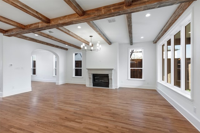 unfurnished living room with hardwood / wood-style floors, beamed ceiling, and a chandelier