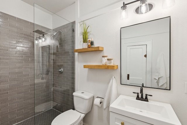 bathroom with toilet, vanity, and tiled shower